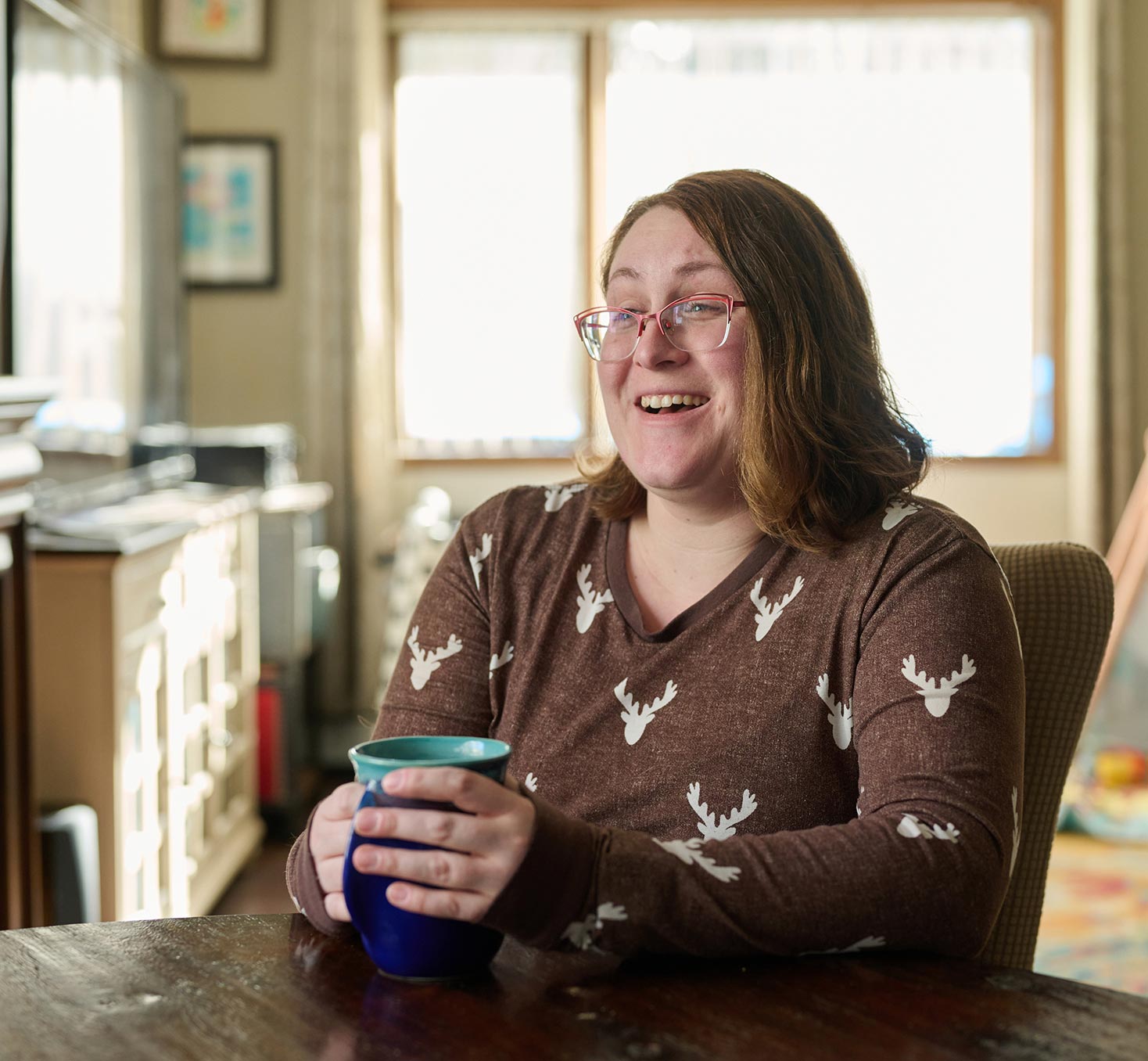 Tija of North Pole, holding a mug and smiling.