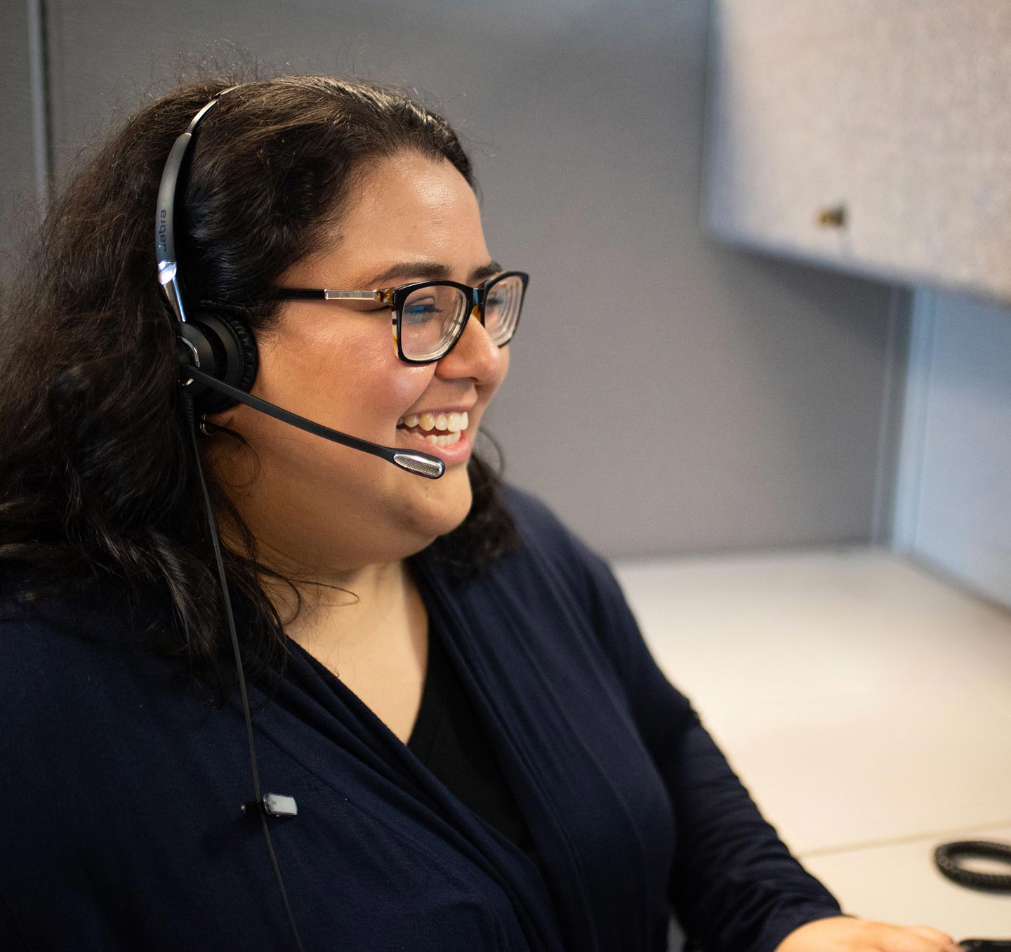 A coach with Alaska's Tobacco Quit Line sitting at her desk, talking on a headset.